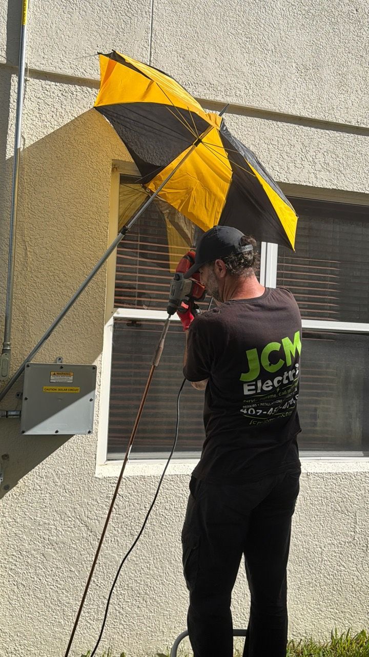 JCM Electric technician using a power tool to install a ground rod beside the house.