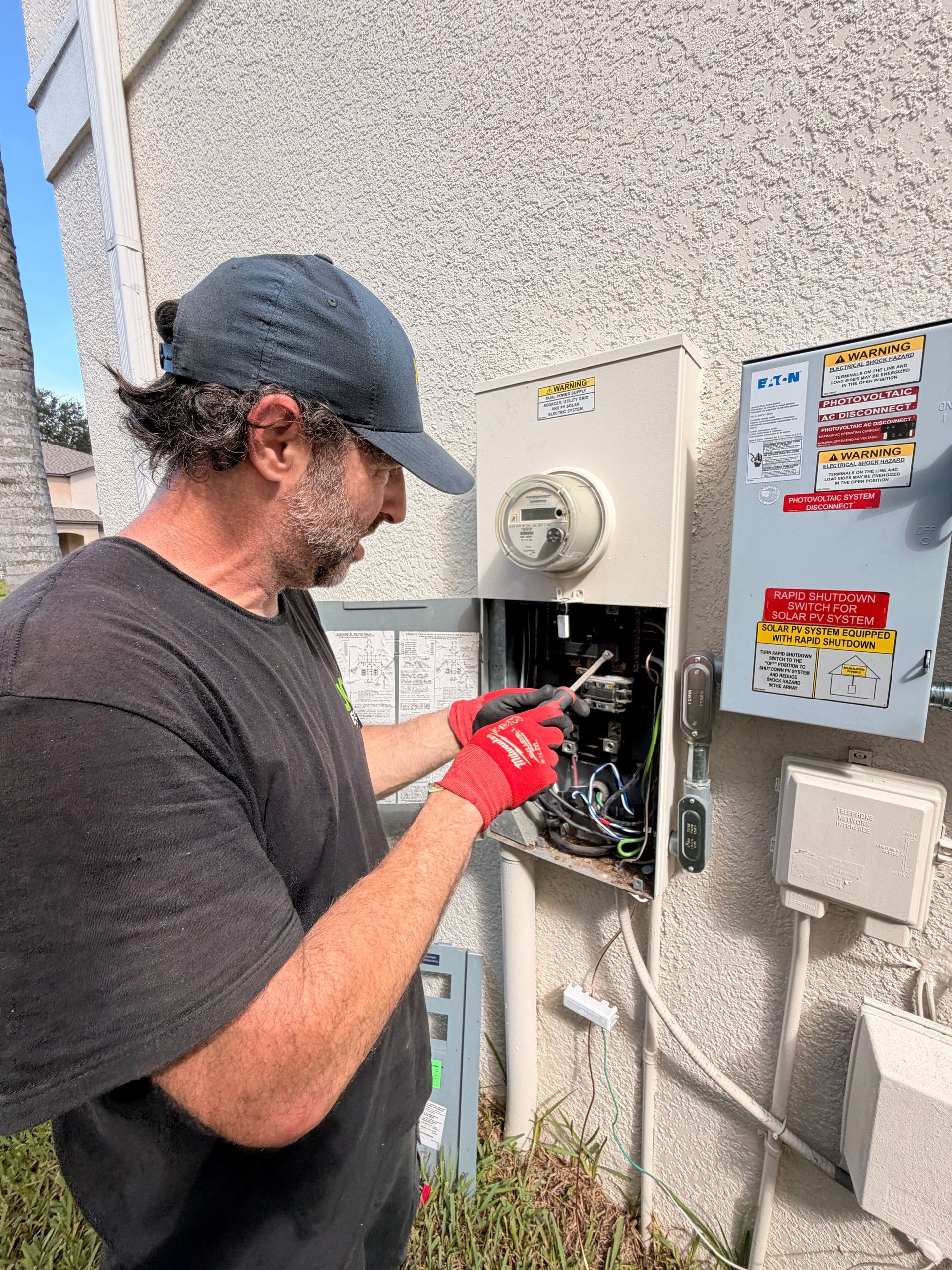 JCM Electric technician working inside the open outdoor service equipment during a grounding upgrade.