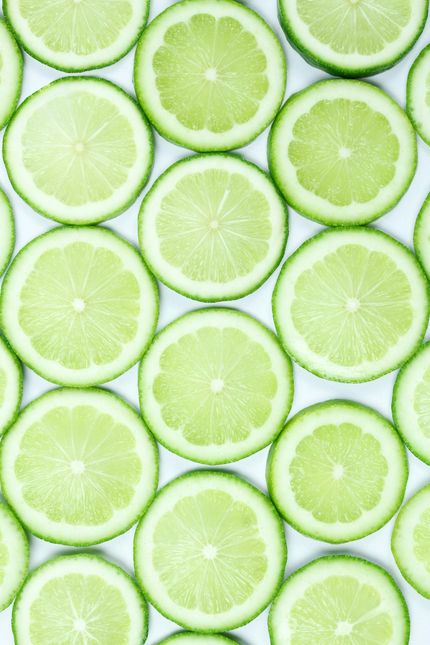 Overlapping slices of fresh green limes on a white background