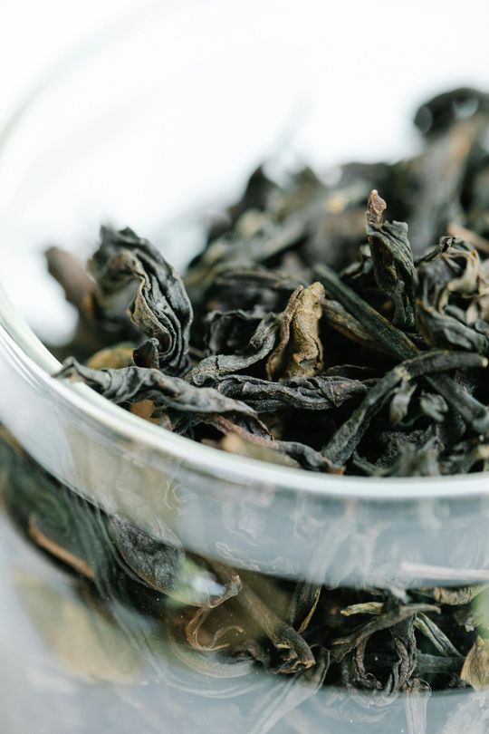 Loose dried tea leaves in a clear glass bowl