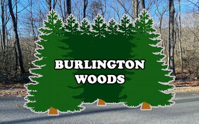 A sign for burlington woods is sitting on the side of a road.