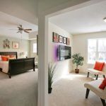 A bedroom with a bed , couch , television and ceiling fan.