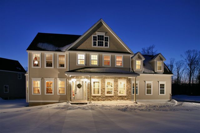 A large house is lit up at night in the snow