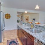 A kitchen with two sinks , a refrigerator , and a clock on the wall.