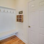 A hallway with a bench , hooks , and a door.