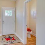 A hallway with a door and a toilet in a house.