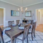A dining room with a wooden table and chairs and a chandelier.