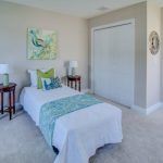 A bedroom with a single bed , nightstands , lamps and a painting on the wall.