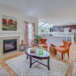 A living room with a coffee table , chairs , fireplace and rug.