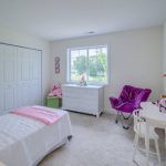 A bedroom with a bed , dresser , chair and window.