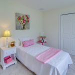 A bedroom with a single bed , nightstand , lamp and painting on the wall.