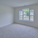 An empty room with two windows and a carpeted floor.