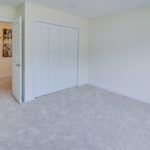 An empty bedroom with a carpeted floor and white walls.