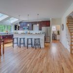 A kitchen with hardwood floors , stools and a staircase.