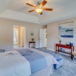 A bedroom with a ceiling fan and a bed.