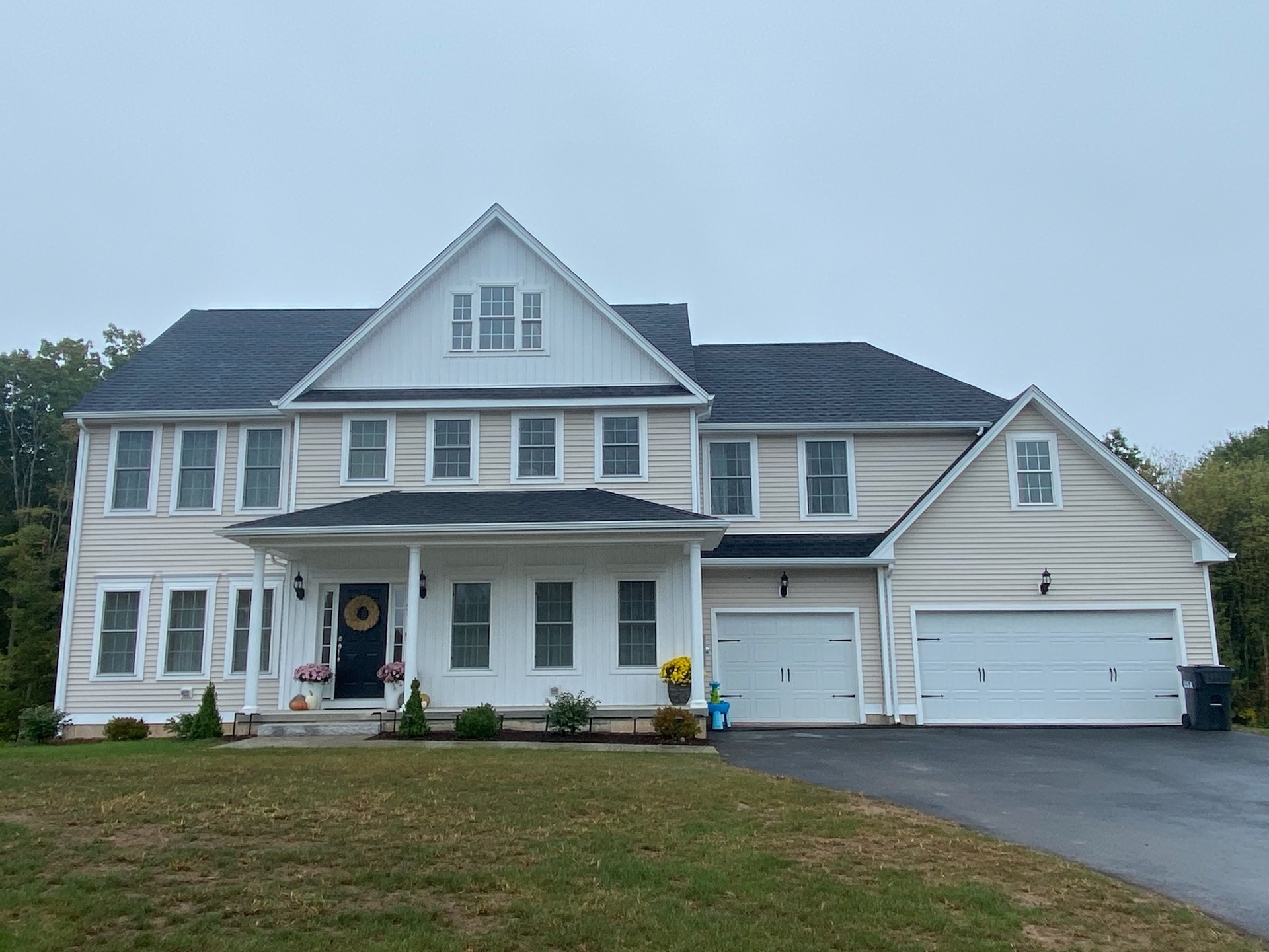A large white house with a black roof and white garage doors