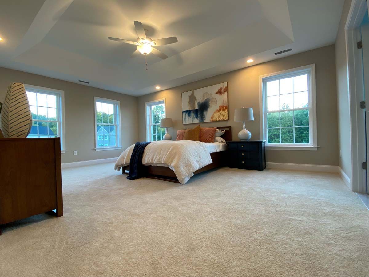 A bedroom with a bed , dresser , nightstands and a ceiling fan.