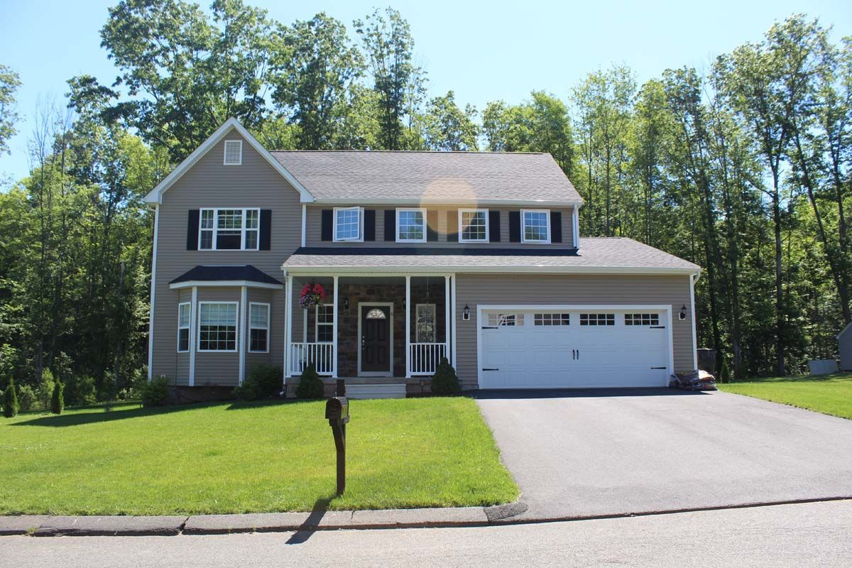 A large house with a white garage door is surrounded by trees