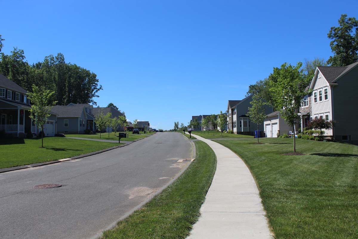 A residential neighborhood with houses and a sidewalk on a sunny day