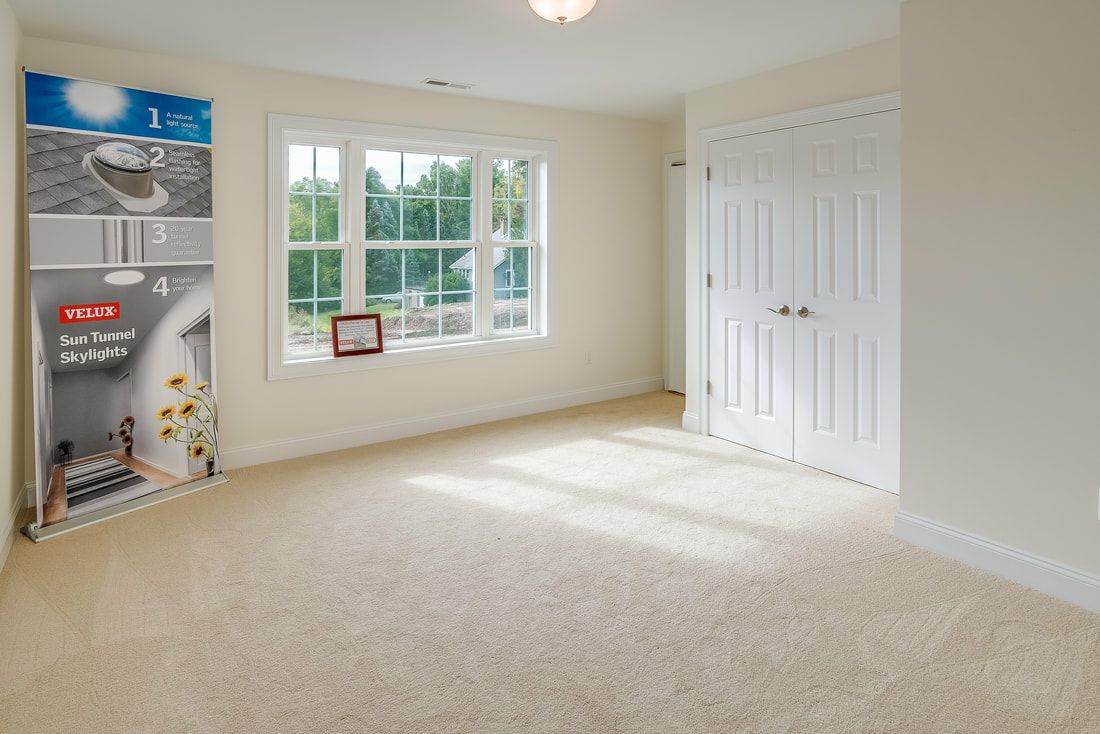 An empty room with a carpeted floor and a window.
