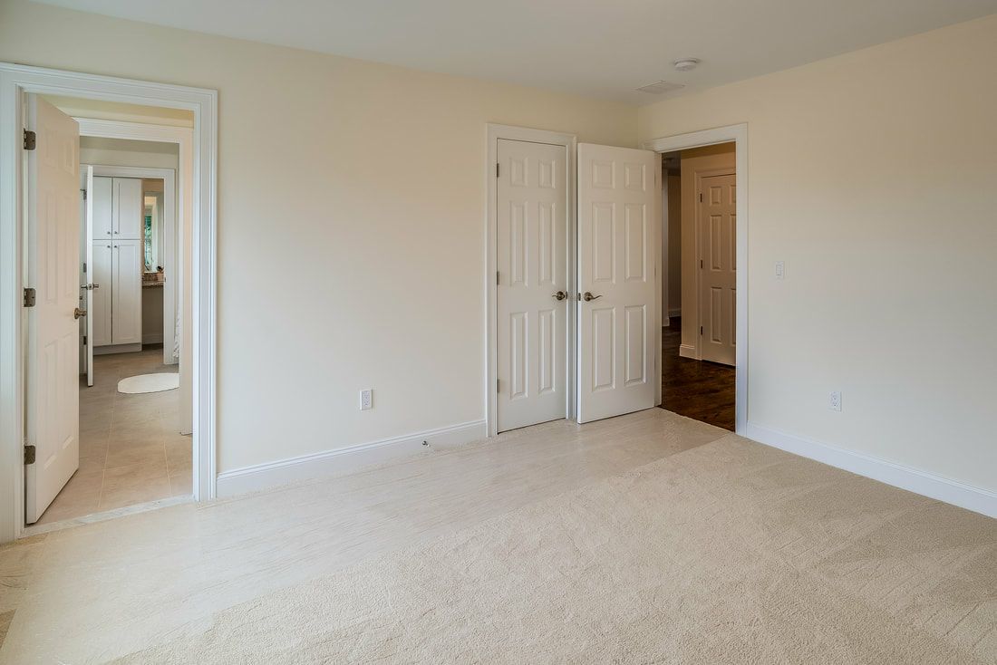 An empty bedroom with a carpeted floor and white walls.