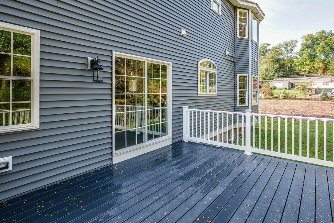 A large deck with a white railing in front of a house.