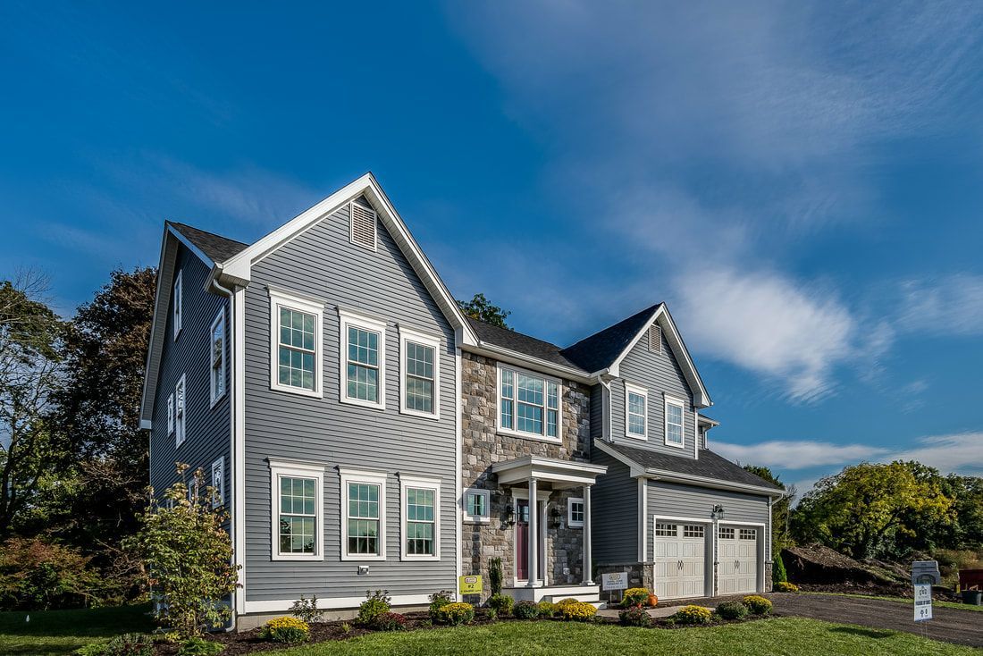 A large gray house with a lot of windows and a blue sky in the background.
