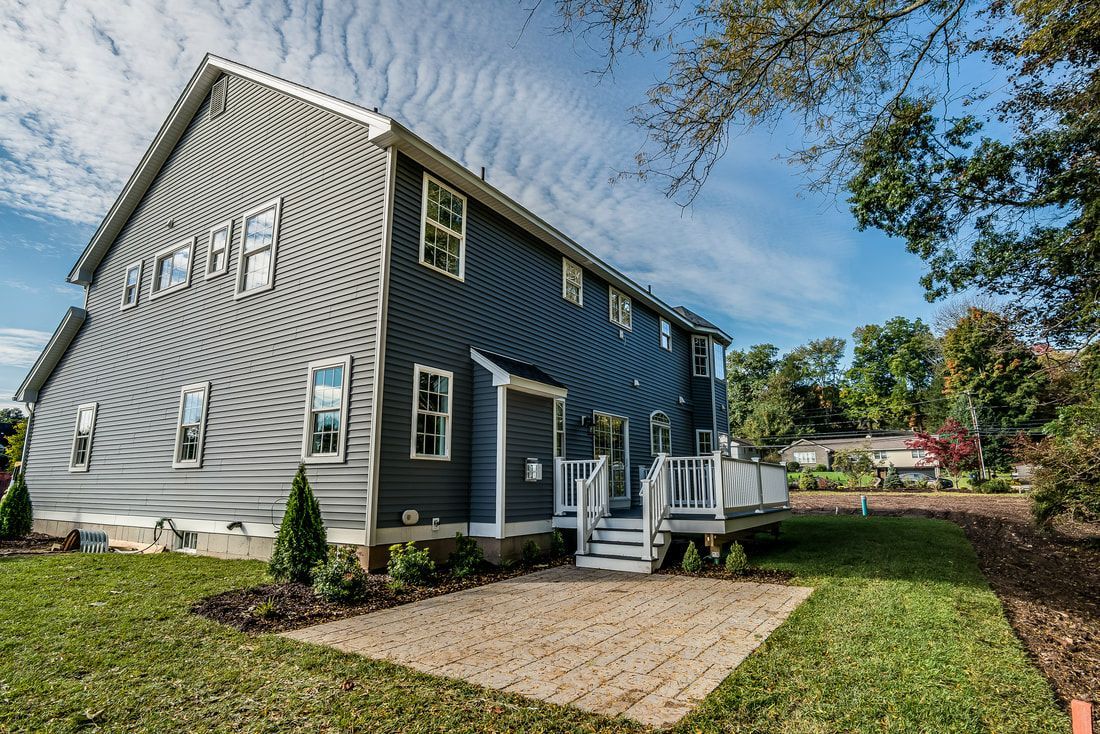 A large gray house with a large lawn in front of it.