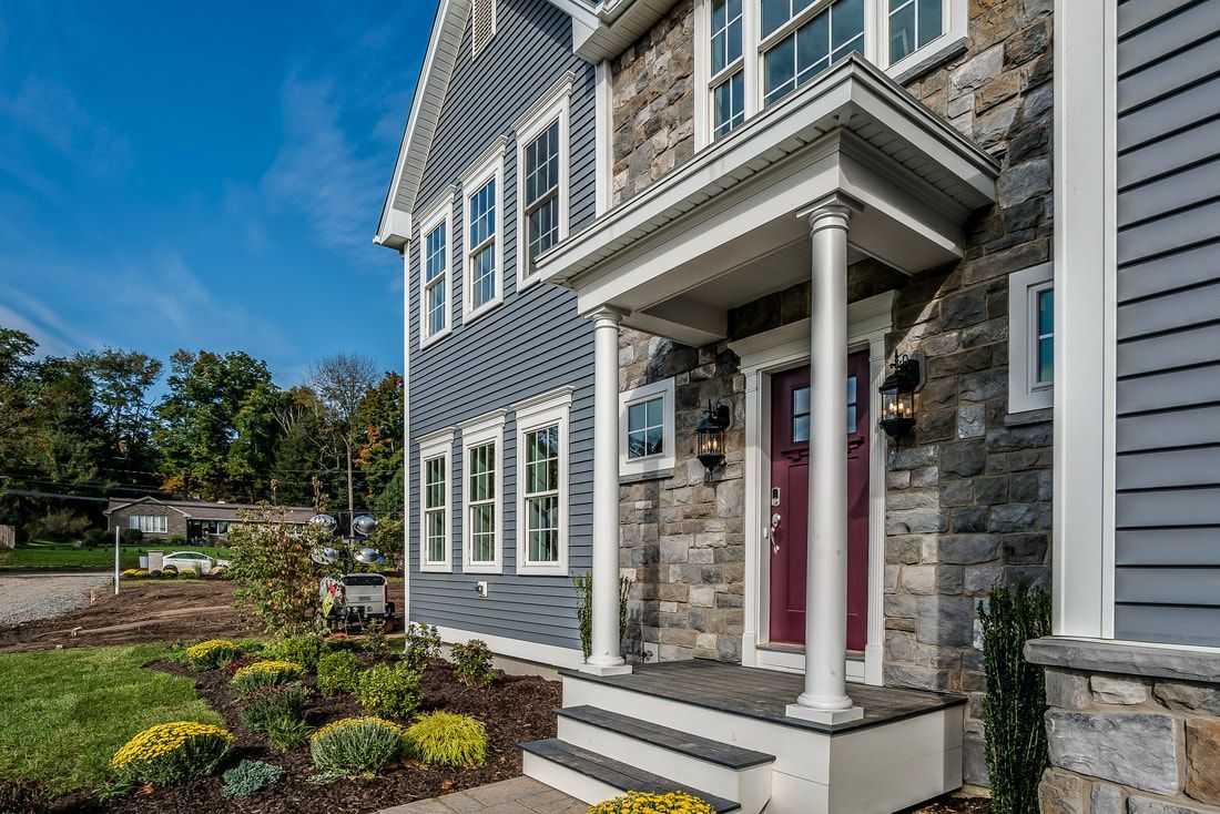 The front of a house with a porch and a red door.