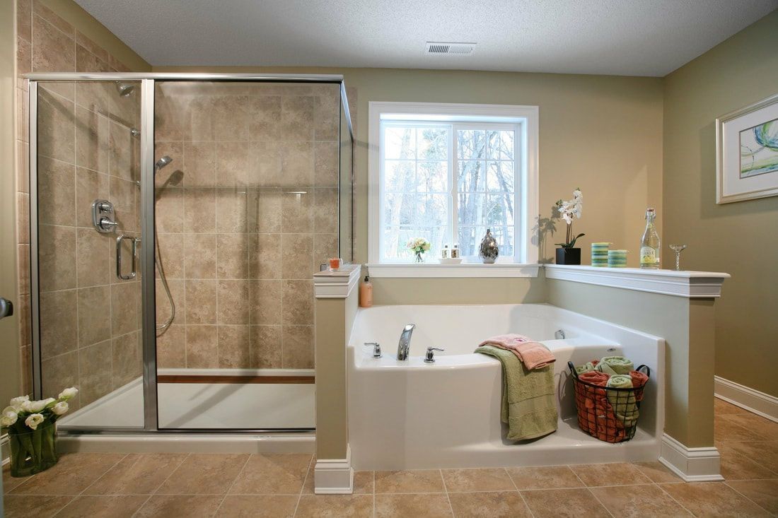 A bathroom with a tub , shower , and window.