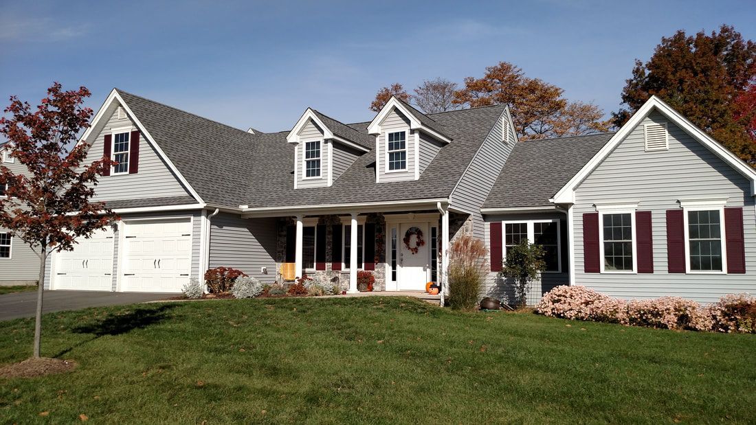 A large white house with a gray roof and red shutters