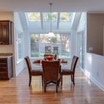 A dining room with a table and chairs and a skylight.