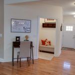 A living room with hardwood floors and a desk and chair.