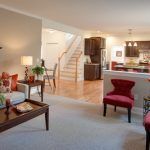 A living room filled with furniture and a staircase leading to the kitchen.