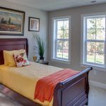 A bedroom with a bed , two windows and a painting on the wall.