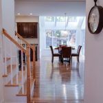 A hallway with stairs leading to a dining room and a clock on the wall.