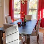 A dining room with a table and chairs and red curtains.