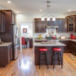 A kitchen with hardwood floors , stainless steel appliances , wooden cabinets , and a large island.