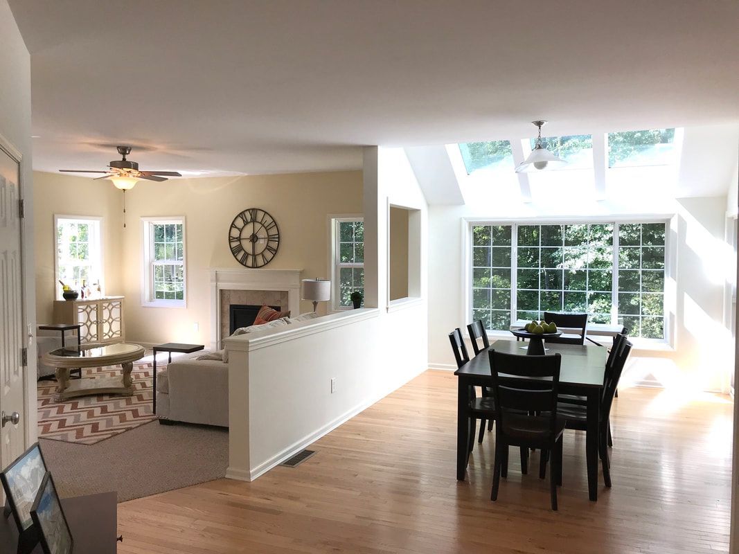A living room with a table and chairs and a clock on the wall.