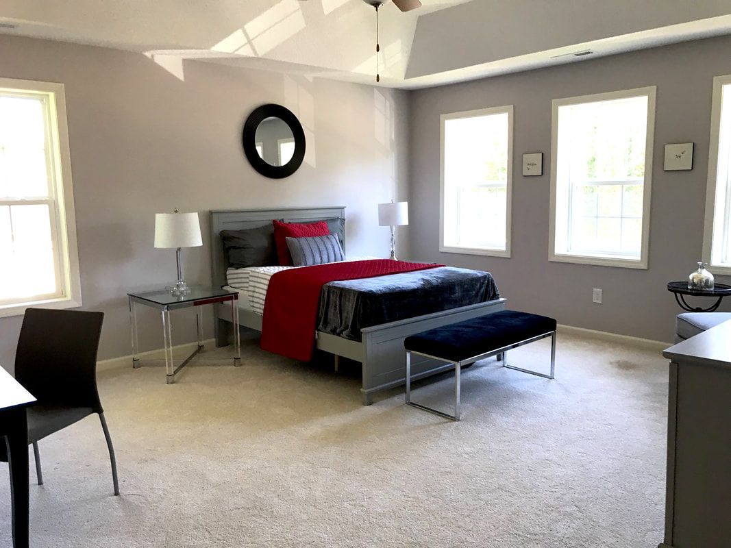 A bedroom with a bed , dresser , chairs and a bench.
