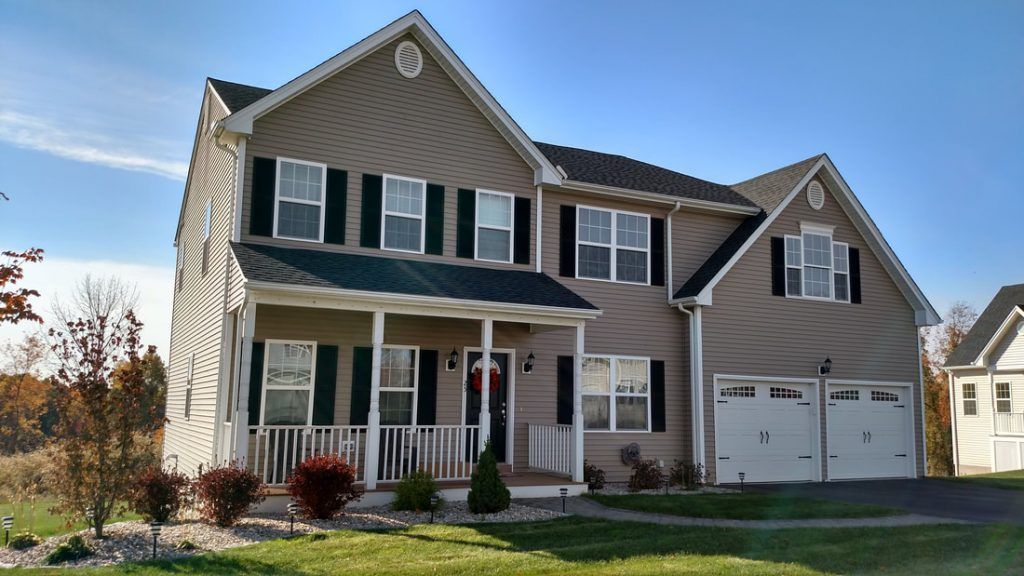A large house with a porch and two garages