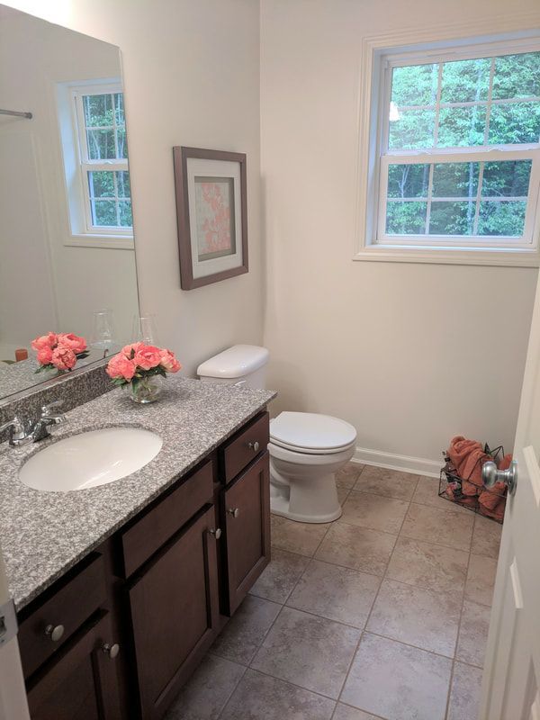 A bathroom with a sink , toilet , mirror and window.