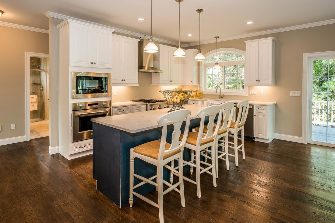 A kitchen with a large island and stools in it.