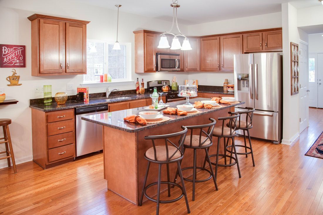 A kitchen with wooden cabinets , stainless steel appliances , and a large island.