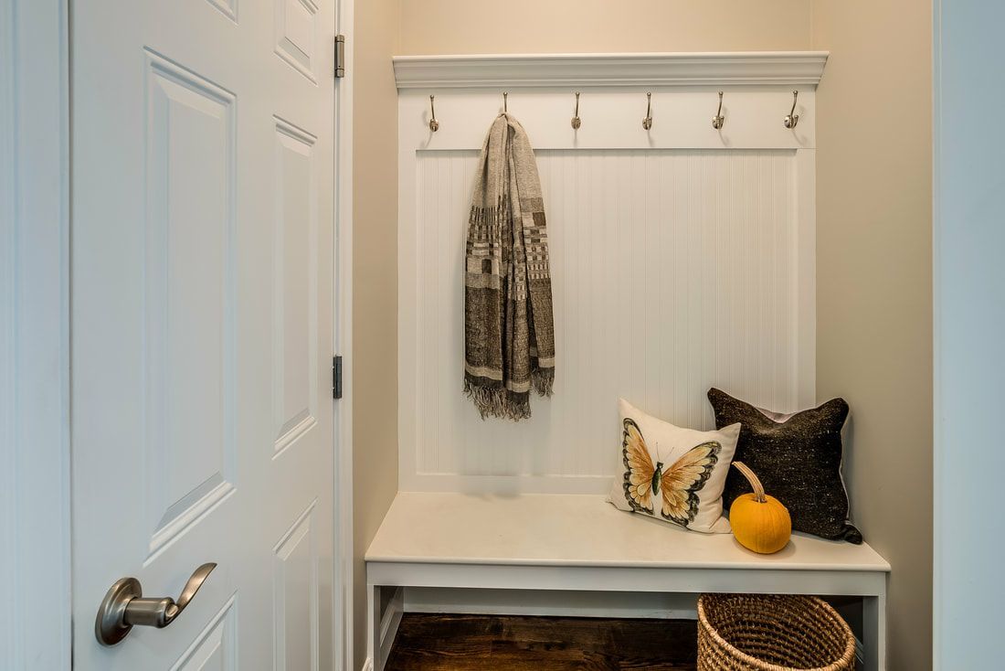 A hallway with a bench and a coat rack.