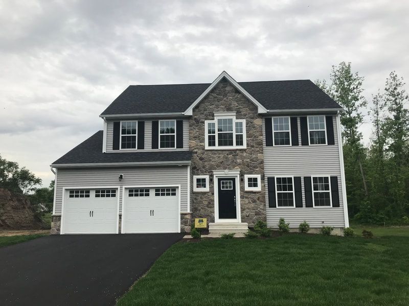 A large house with a black roof and white garage doors