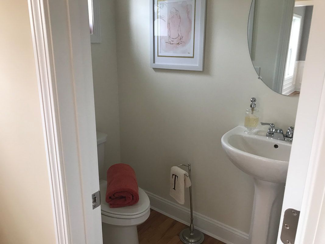A bathroom with a toilet , sink and mirror.