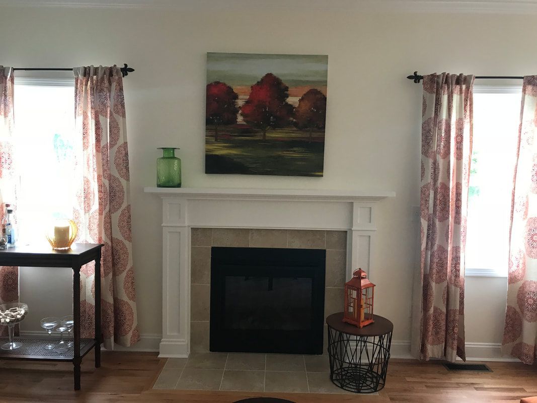 A living room with a fireplace and a painting on the wall above it.