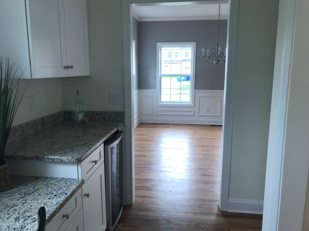 A kitchen with granite counter tops and white cabinets leading to a dining room.