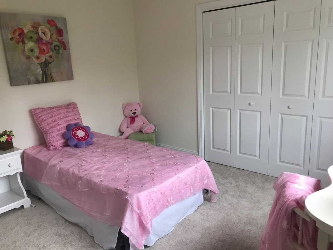 A bedroom with a pink bed and a teddy bear.